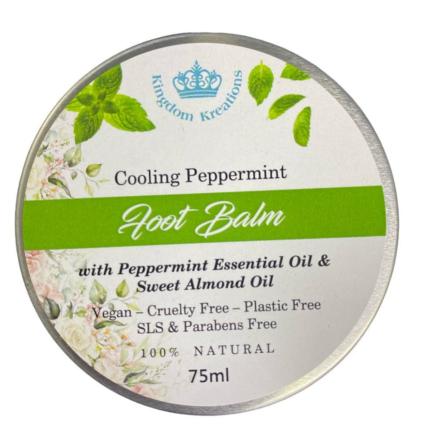A round container of Kingdom Kreations Cooling Peppermint Foot Balm with a label that includes the product name, a brief description, and the statement '100% Natural'. The container indicates it's 75ml and has a green and white color scheme with floral elements.