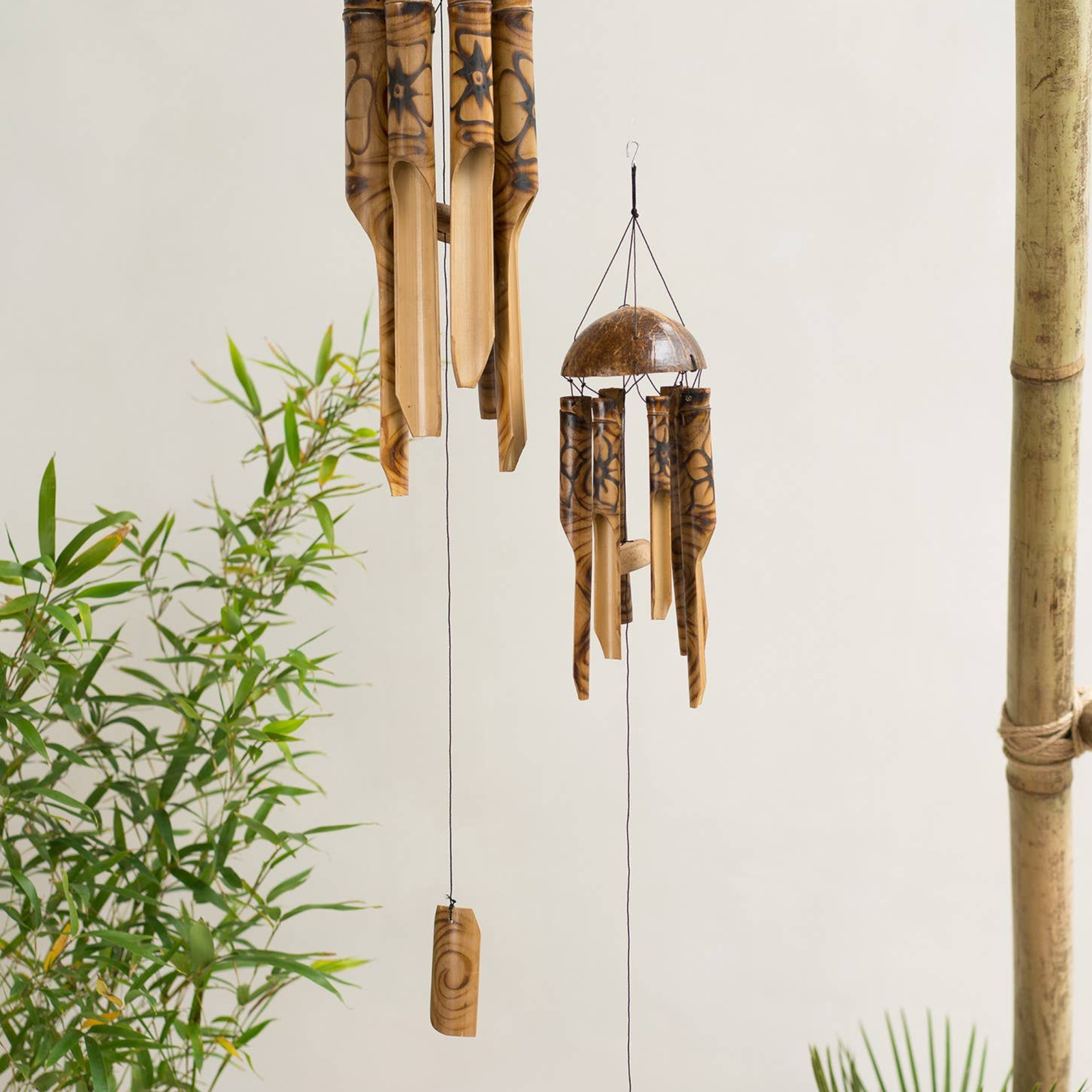 Bamboo wind chime with green plants on a light background