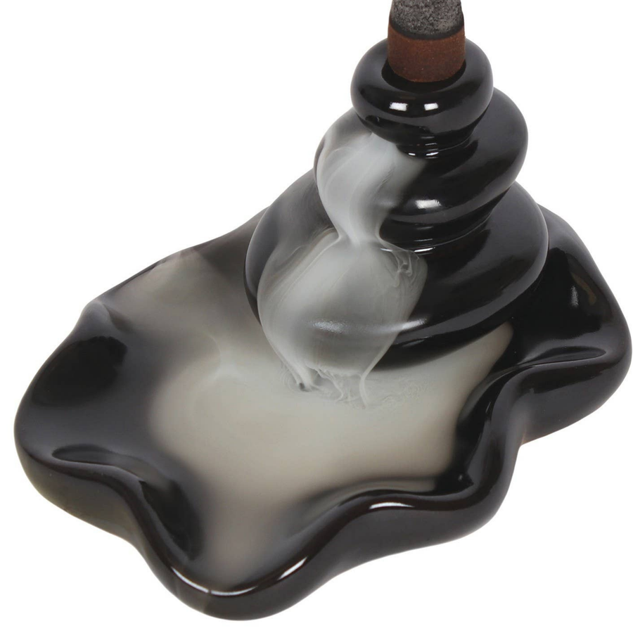 Black and white ceramic incense burner with a wavy design on a white background