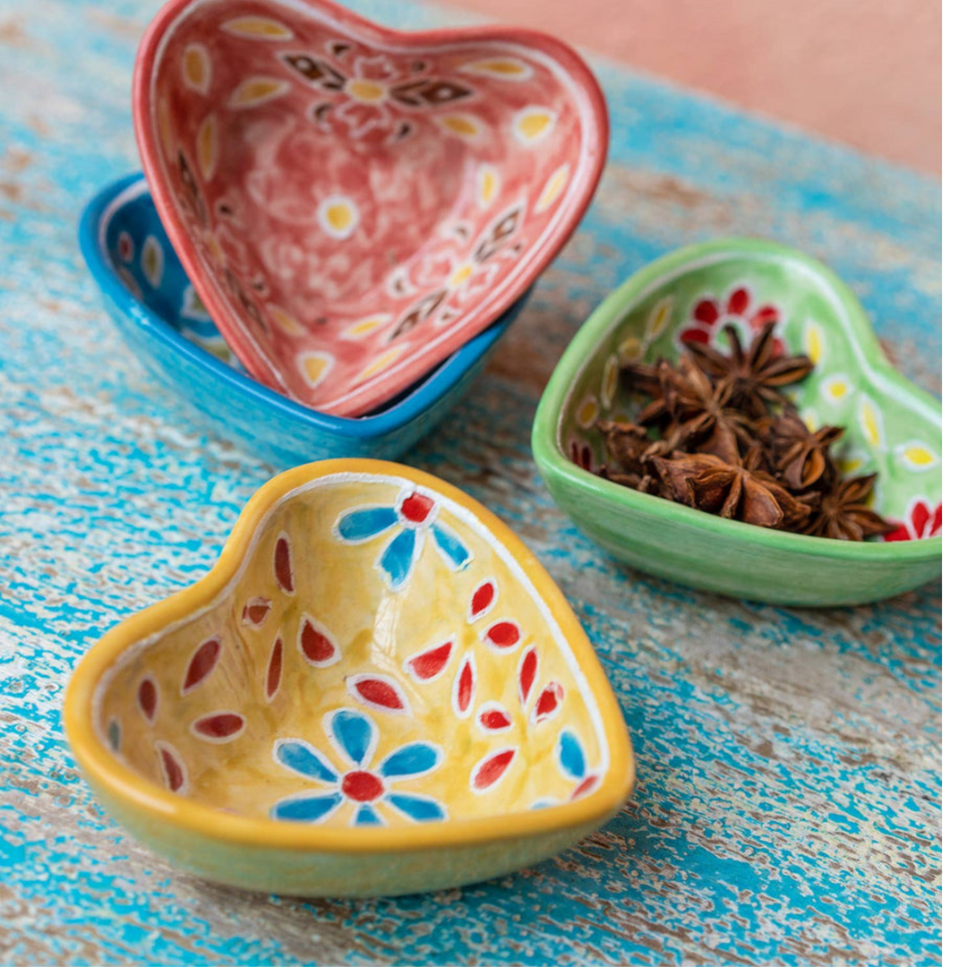 Hand painted ceramic heart-shaped dishes in different colors with floral patterns. Red, Blue, Yellow, Green.