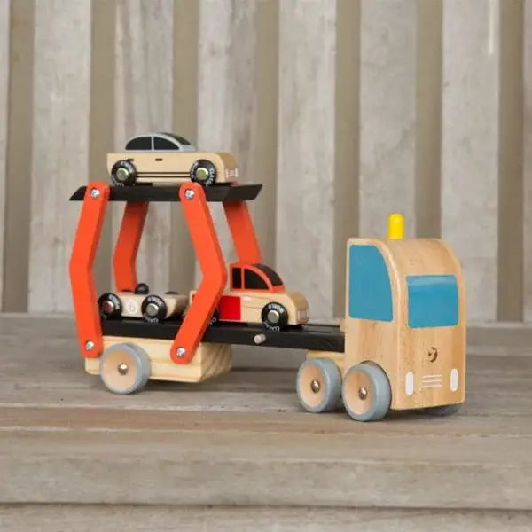 Wooden toy truck with a trailer carrying smaller toy cars on a wooden surface.