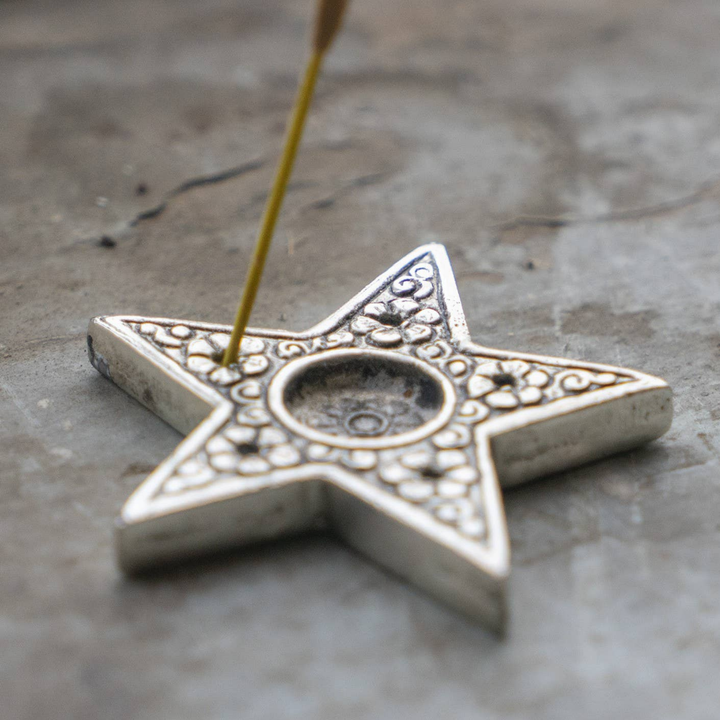 Star-shaped metal object with intricate designs on a textured surface