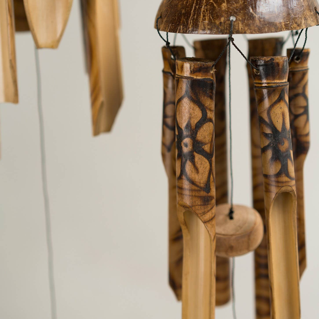 Wooden wind chime with intricate carvings on a plain background