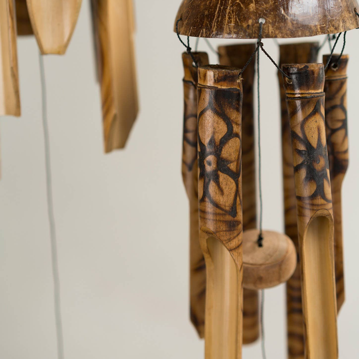Wooden wind chime with intricate carvings on a plain background