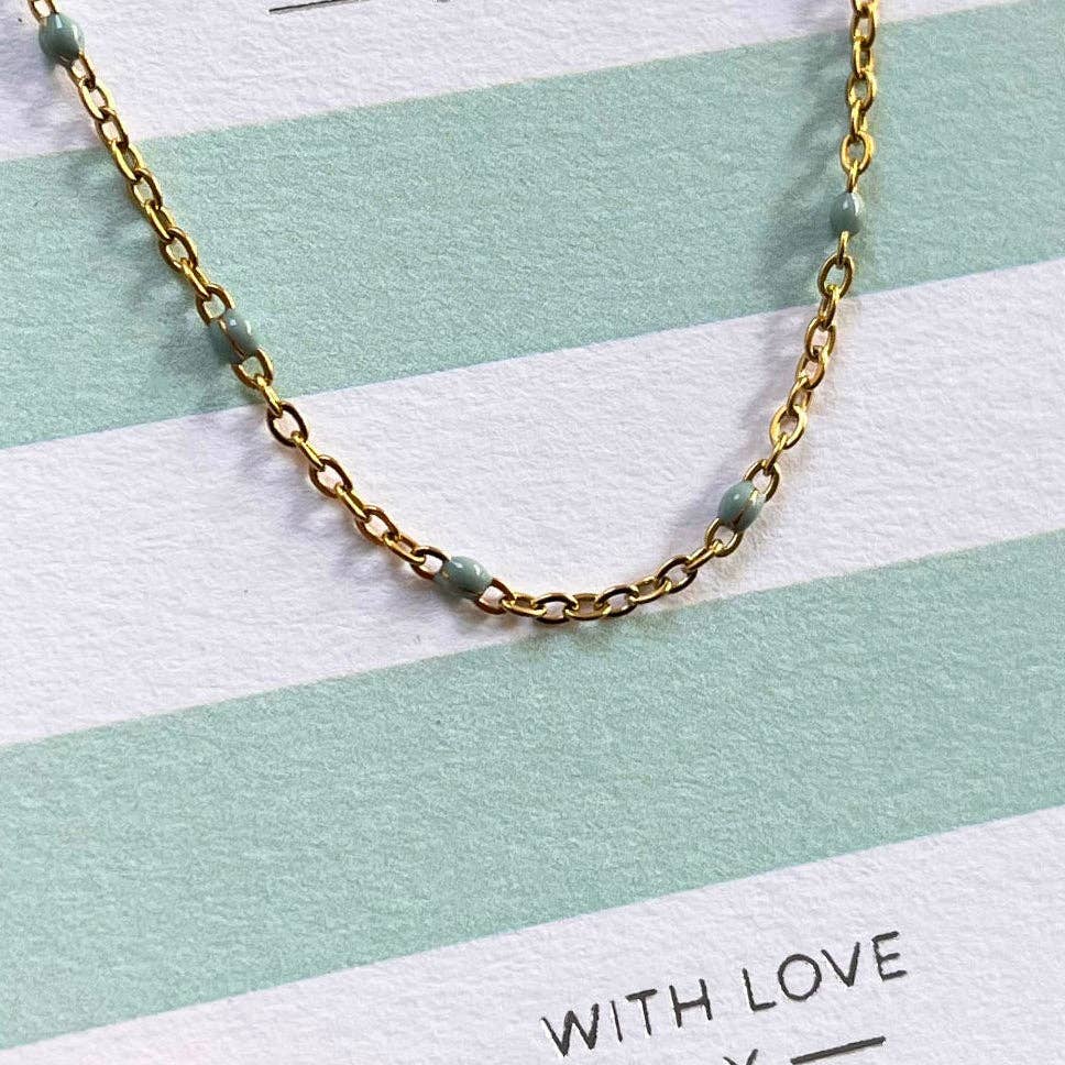 Gold chain necklace on a striped background with 'WITH LOVE' text