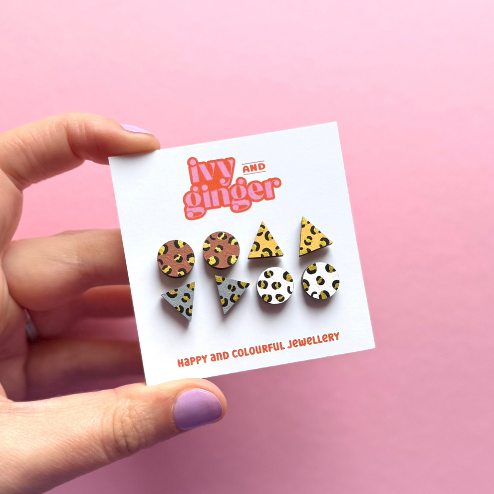 Set of colorful leopard earrings on a 'Ivy and Ginger' branded card against a pink background