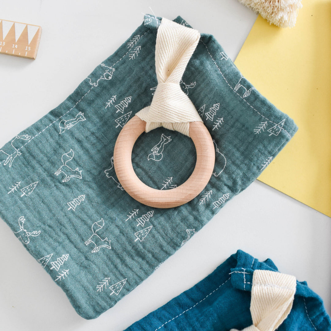 Wooden teething ring on a teal fabric with white patterns