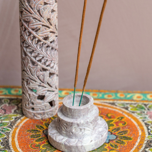 Decorative stone incense holder with incense sticks on a colorful surface