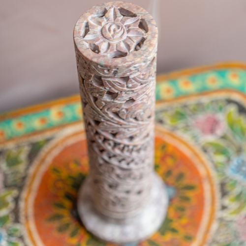 Decorative cylindrical object with intricate carvings on a colorful plate