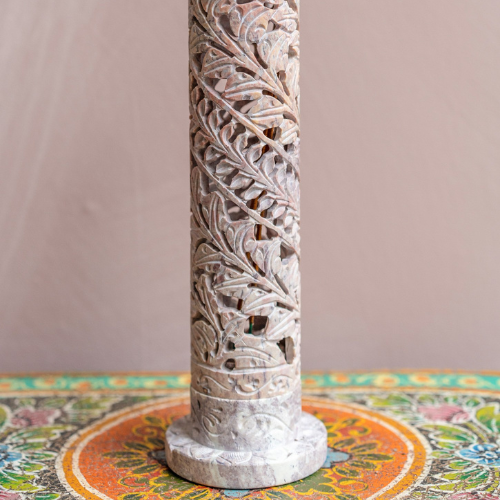 Decorative carved column on a colorful tablecloth with a plain background
