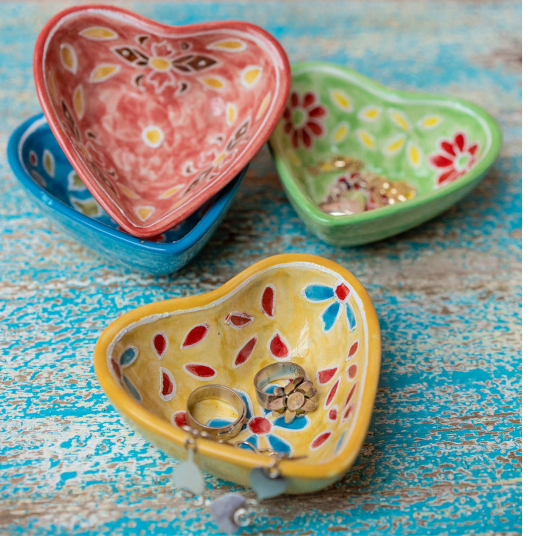 Hand painted ceramic heart-shaped dishes in different colors with floral patterns. Red, Blue, Yellow, Green.