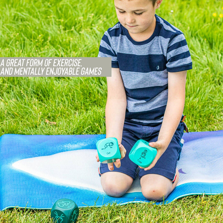 Child playing with green yoga dice on a blue mat in a grassy area
