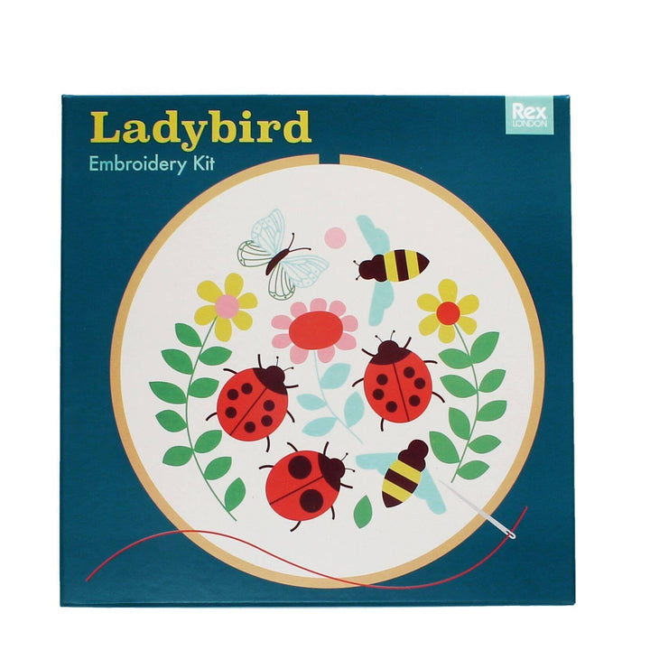 Embroidery kit packaging with ladybugs, flowers, and bees on a blue background