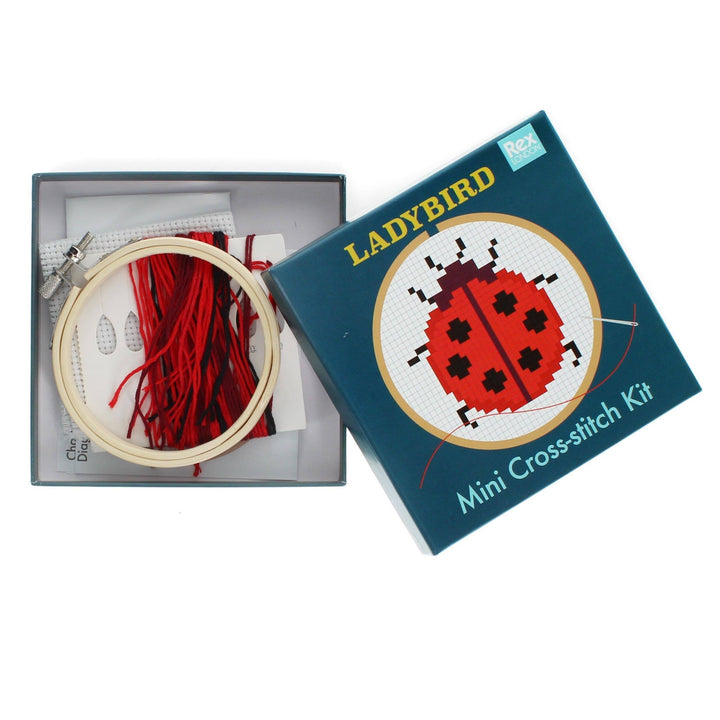 Cross-stitch kit with embroidery hoop and red thread, featuring a Ladybird design on the packaging.
