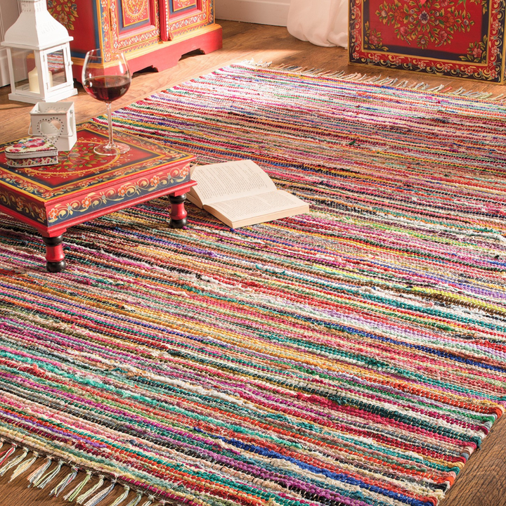 Multicolored striped rug with a small table and decorative items in the background.