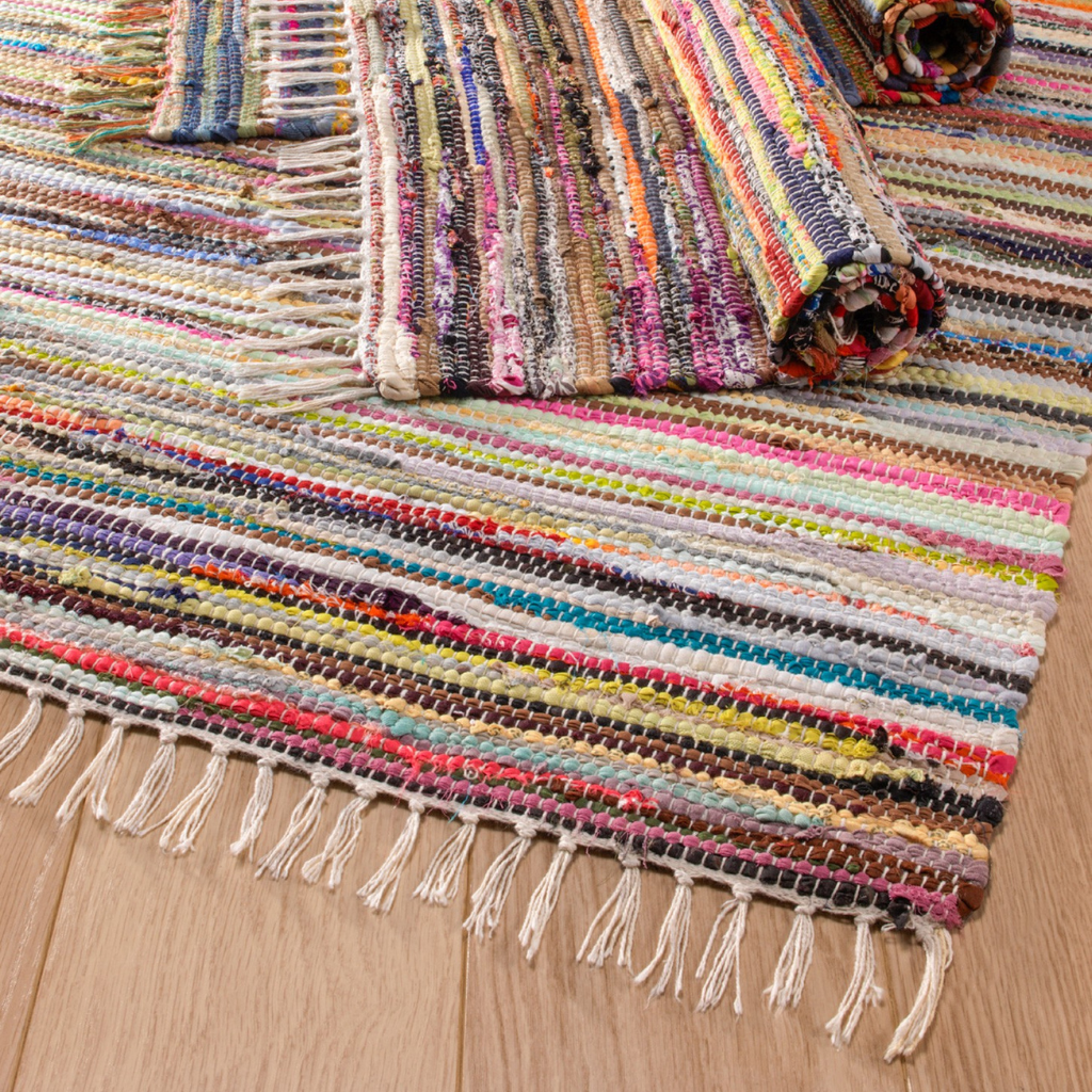 Multicolored woven rug with fringe on a wooden floor