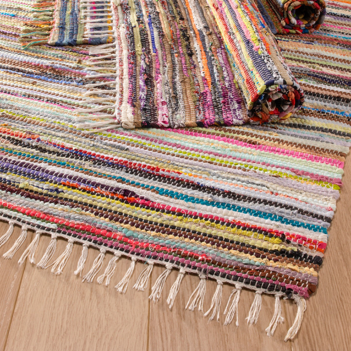 Multicolored woven rug with fringe on a wooden floor