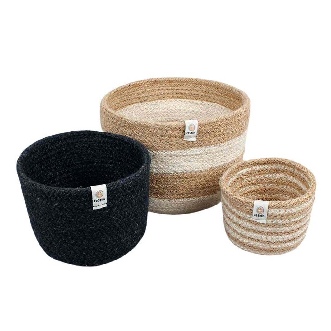 A set of three woven jute baskets in varying sizes, featuring natural and black colours with horizontal stripes. The baskets are tall and cylindrical, designed to be stackable.