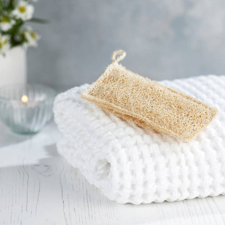 Loofah sponge on a white textured surface with a blurred background