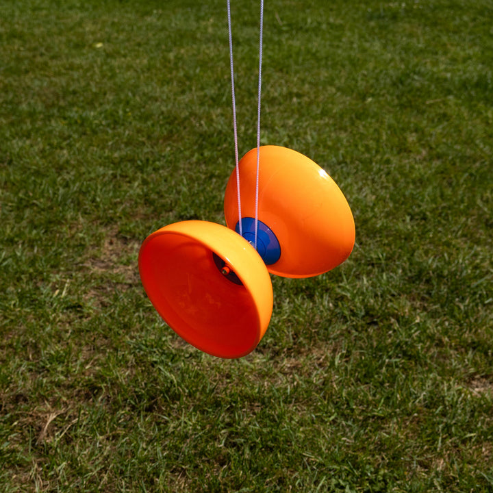 Orange and red yoyo on a string against a grassy background