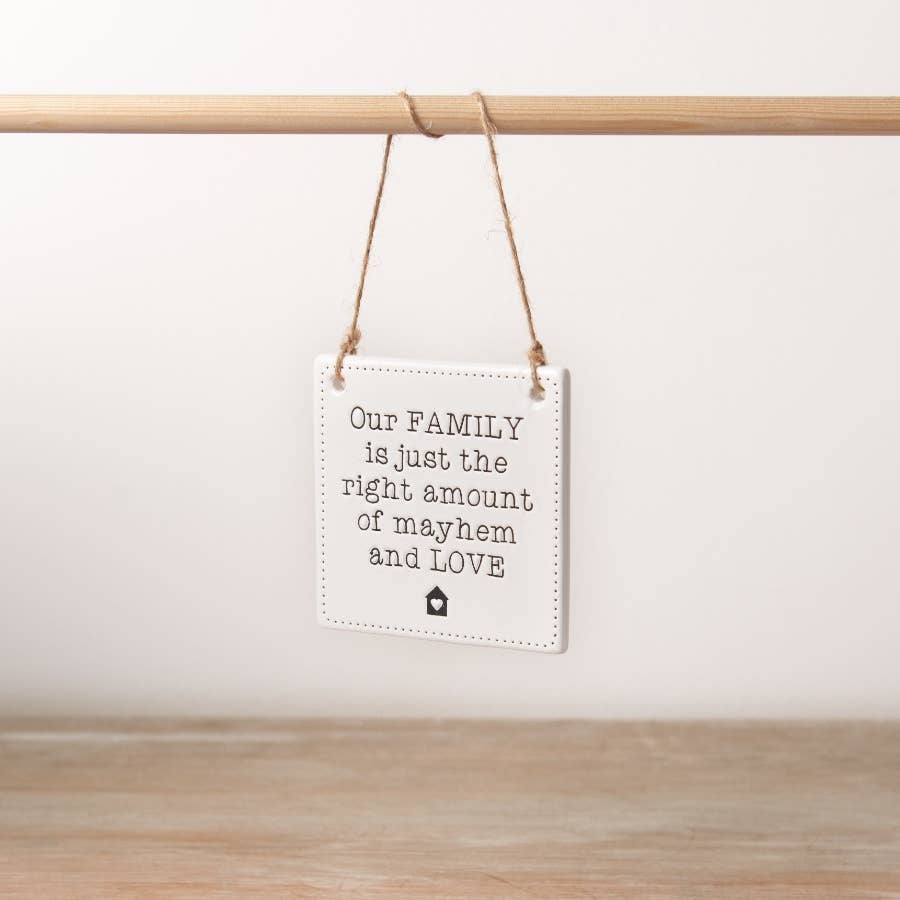 A chic engraved ceramic sign with a rustic jute string hanger with the phrase our family is just the right amount of mayhem and love. 