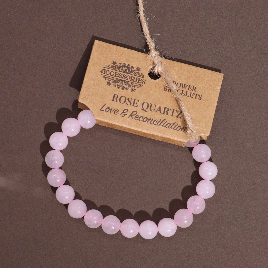 A pink bracelet made of rose quartz beads, displayed on a cardboard retail packaging with the brand name 'Ancient Wisdom'.