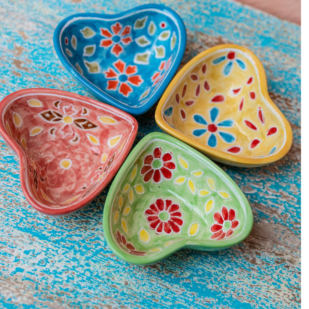 Hand painted ceramic heart-shaped dishes in different colors with floral patterns. Red, Blue, Yellow, Green.