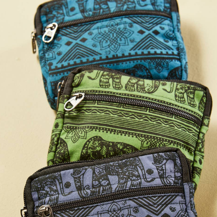 Three patterned coin purses, Blue, Green and purple with a black printed elephant design stacked on a beige background.
