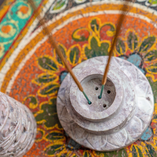 Incense stick holder with incense sticks on a colorful, patterned surface