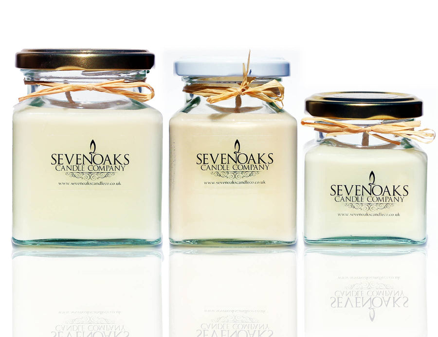 Three glass jars with white candles inside, each adorned with a raffia ribbon and a label reading 'SEVENOAKS'. The jars vary in size and are displayed against a white background.
