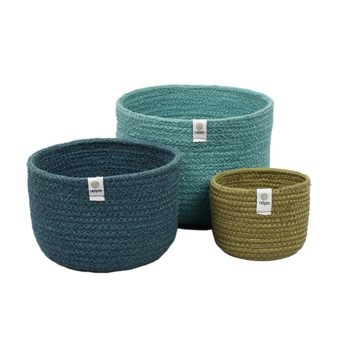 Set of three tall nesting baskets made from brightly colored jute, inspired by the sea. Each basket has a round shape and a label attached to the side.