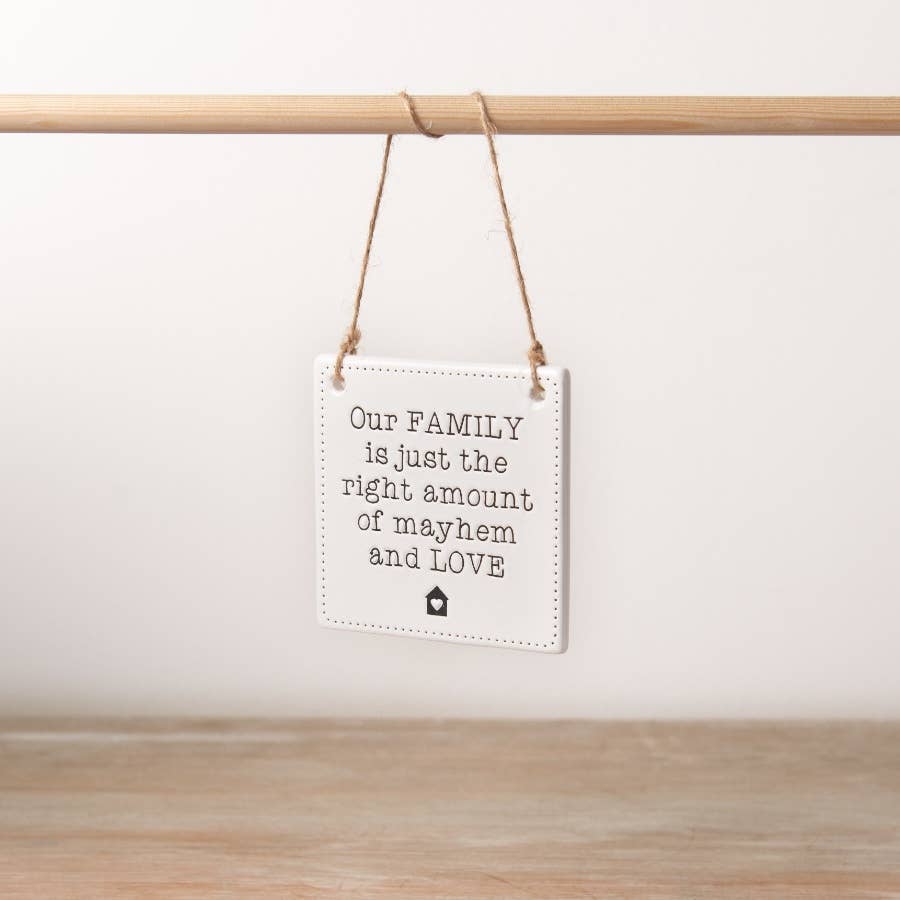 A chic engraved ceramic sign with a rustic jute string hanger with the phrase our family is just the right amount of mayhem and love. 