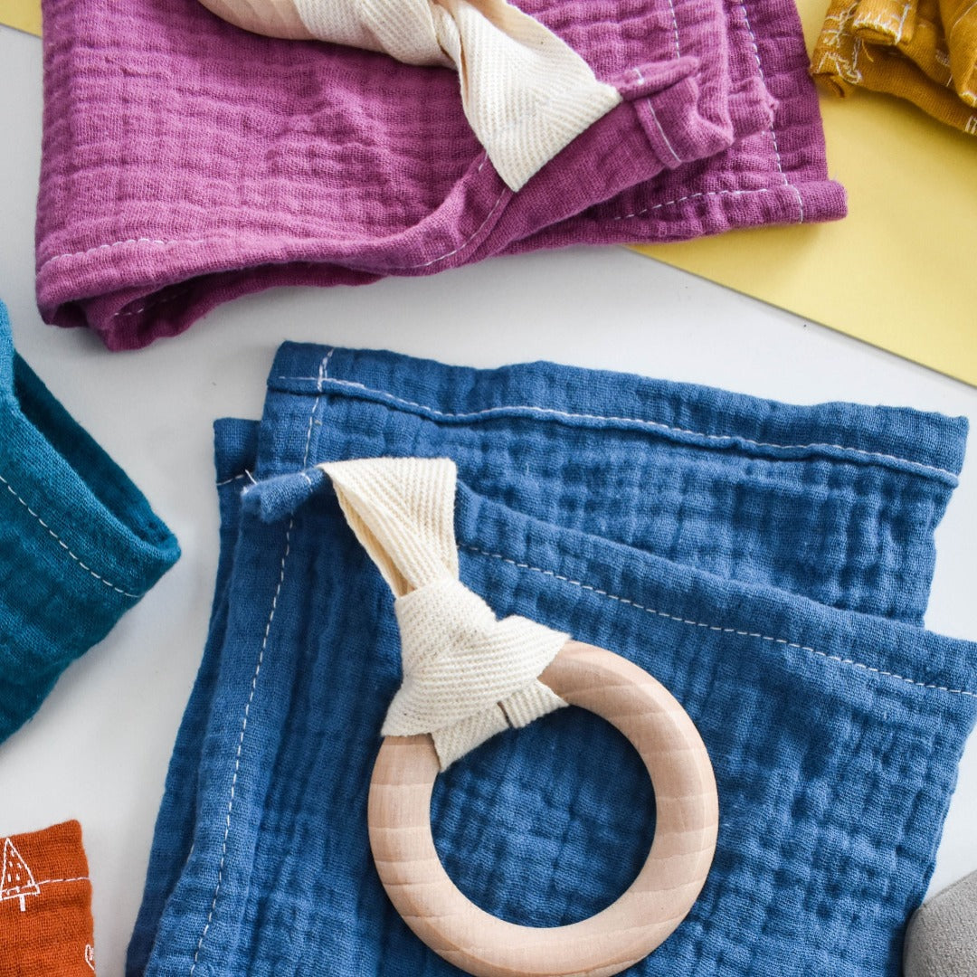 Baby teether comforter with beechwood teether ring and blue muslin comforter.