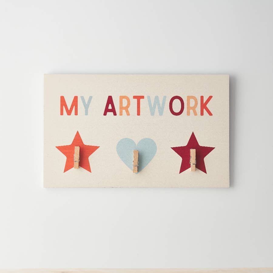 Wooden board with my artwork painted on top with three clips to add artwork to the board.