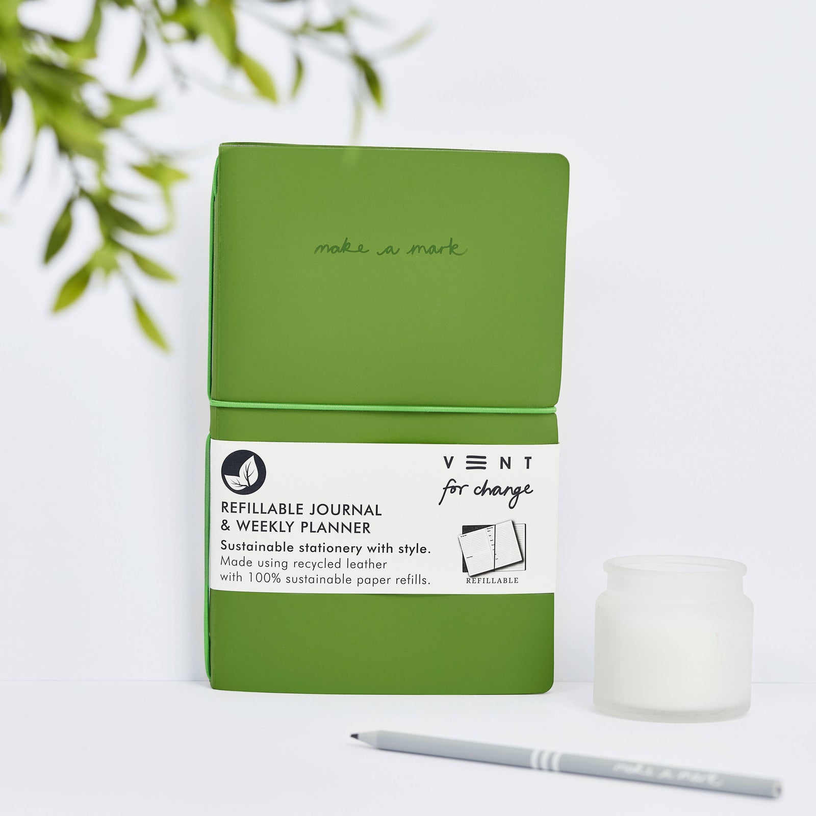 A green refillable weekly planner and lined notes with a recycled leather cover, displayed alongside a white dotted refill and a grey pencil.
