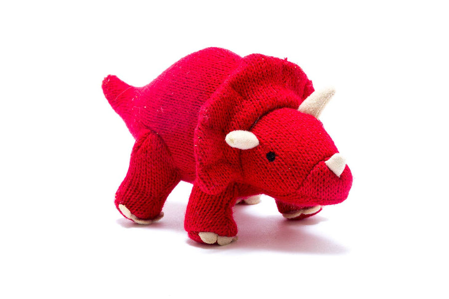 A small red knitted dinosaur baby rattle shaped like a Triceratops.